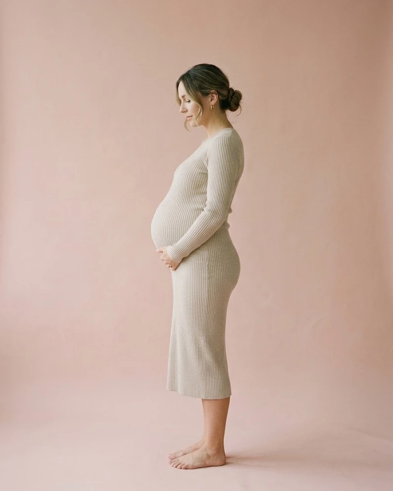A pregnant woman in profile, hand under her bump